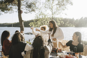 Cheerful multiracial female friends doing celebratory toast on sunny day - MASF26811