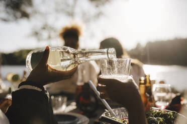 Abgeschnittene Hand einer Frau, die einem Freund beim Abendessen Wein in ein Glas gießt - MASF26814