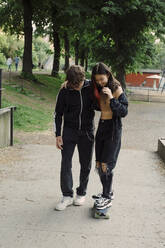 Teenager, der einer Freundin im Park das Skateboarden beibringt - MASF26868