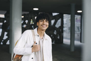 Smiling teenage boy with backpack in parking garage - MASF26893