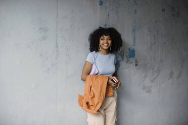 Porträt eines lächelnden Teenagers, der an einer grauen Wand steht - MASF26898