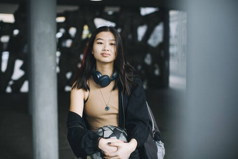 Portrait of teenage girl with sports ball in parking garage - MASF26900