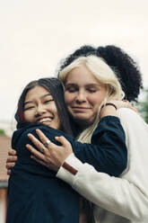 Lächelnde multirassische Freundinnen umarmen sich im Park - MASF26938
