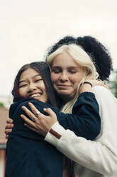 Smiling multiracial female friends embracing in park - MASF26938