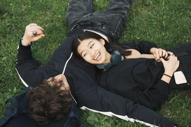 High angle view of male and female friends lying on grass at park - MASF26958