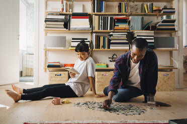 Mann spielt Puzzle, während seine Freundin im Wohnzimmer ein Buch liest - MASF27000