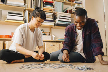 Lächelndes Paar spielt Puzzle auf dem Boden zu Hause - MASF27006