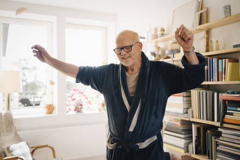 Älterer Mann im Bademantel tanzt im Wohnzimmer zu Hause - MASF27025