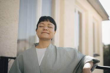 Young woman standing with eyes closed in balcony - MASF27084