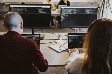 Männlicher und weiblicher Programmierer beim Programmieren am Laptop in einem Startup-Unternehmen - MASF27141