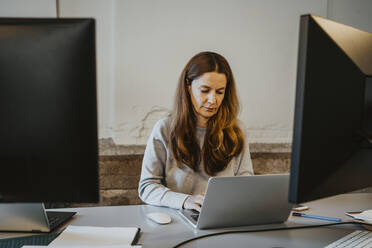 Reife Programmiererin bei der Arbeit am Laptop im Büro - MASF27160