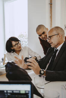 Älterer männlicher Investor diskutiert mit Kollegen im Büro eines Start-up-Unternehmens - MASF27183