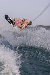 Young man doing waterskiing stunt on lake - DAWF02082
