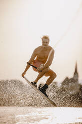 Mann ohne Hemd fährt Wasserski auf einem See - DAWF02085