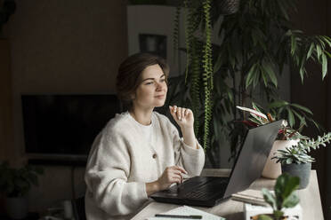 Businesswoman with laptop working at home - LLUF00272