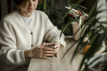 Frau hält Teetasse auf Holztisch - LLUF00275