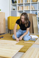 Junge Frau beim Zusammenbau eines Möbelstücks - GIOF13976
