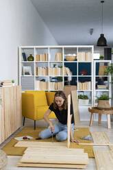 Frau mit Schraubenzieher beim Zusammenbau von Möbeln zu Hause - GIOF13978