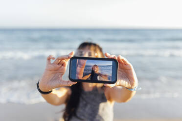 Junge Frau nimmt Selfie durch Smartphone am Strand - EGHF00217