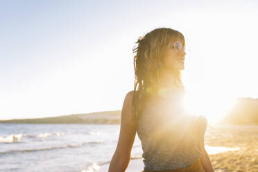 Lächelnde Frau mit Sonnenbrille am Strand - EGHF00218