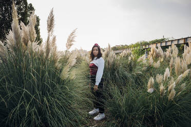 Woman with headband standing amidst grass - MEUF04662