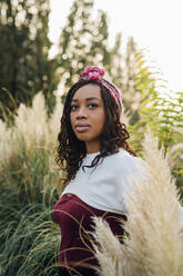 Woman wearing headband standing at meadow - MEUF04664