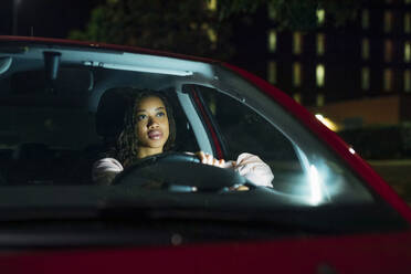 Junge Frau fährt beleuchtetes Auto bei Nacht - MEUF04709