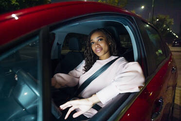 Lächelnde junge Frau am Steuer eines Autos - MEUF04710