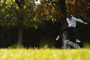 Junger Mann fährt Skateboard auf Gras - SSGF00176