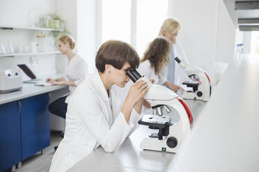 Forscher mit Mikroskop, im Hintergrund arbeiten Kollegen - AHSF02810