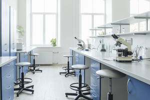 Microscopes at desk in bright empty laboratory - AHSF02828