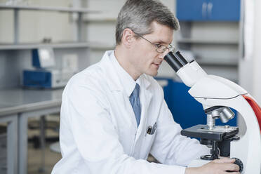 Researcher checking sample through microscope in laboratory - AHSF02840