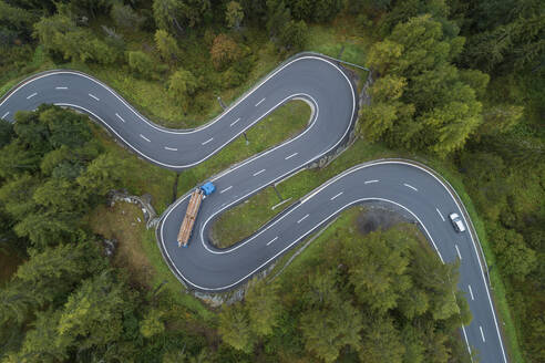 Drohnenansicht eines Holzfällerfahrzeugs auf der kurvenreichen Maloja-Passstraße - RUEF03420