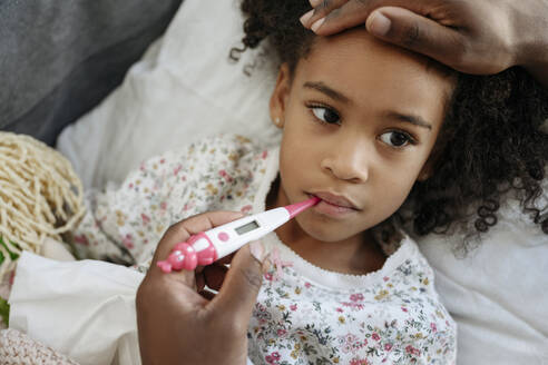 Man with thermometer checking fever of daughter at home - VYF00601