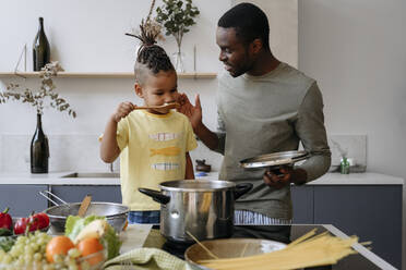 Junger Mann spricht mit seinem Sohn und riecht Spaghetti in der Küche - VYF00624