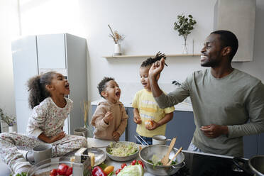 Man playing with family in kitchen - VYF00644
