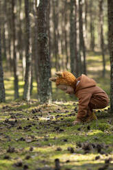 Mädchen sammelt Tannenzapfen im Wald - SSGF00190