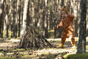 Mädchen hält Pflanzenstock im Wald - SSGF00191