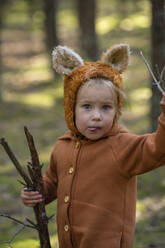 Nettes Mädchen mit Holzstöcken, die ihre Zunge im Wald herausstrecken - SSGF00207