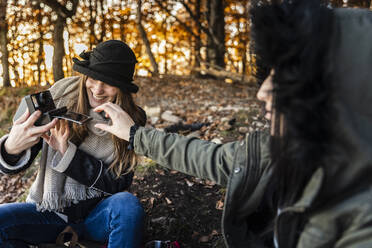 Glückliche junge Frauen beim Fotografieren im Herbstwald - MCVF00933