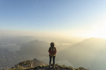 Female hiker looking at landscape from mountain peak, Lecco, Italy - MCVF00935