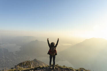Female hiker with arms raised on mountain peak at Orobie Alps, Lecco, Italy - MCVF00936