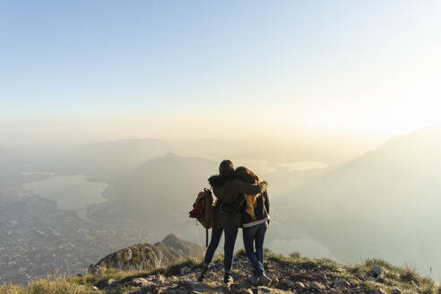 Frau umarmt Freund auf Berggipfel in Lecco, Italien - MCVF00937