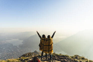 Sorglose Frauen mit erhobenen Armen auf einem Berggipfel in den Orobie-Alpen, Lecco, Italien - MCVF00940