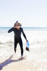 Männlicher Freiwilliger mit Helm und Netzbeutel am Meer - EGHF00230