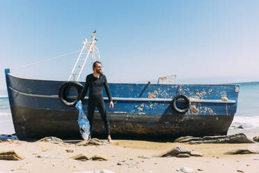 A man in a wetsuit, standing on the shore with a large spear fishing harpoon.  stock photo