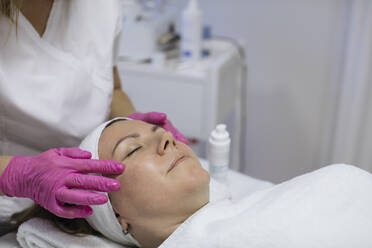 Kosmetikerin bei der Gesichtsmassage einer reifen Frau im Salon - MOMF00951