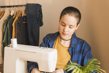 Eine Modedesignerin näht in einer Werkstatt Kleider an einer Maschine - MGRF00567