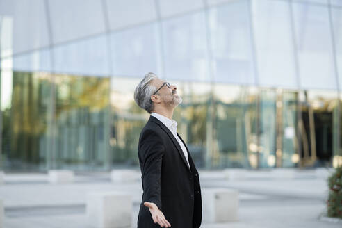 Businessman looking up with arms outstretched - JCCMF04402