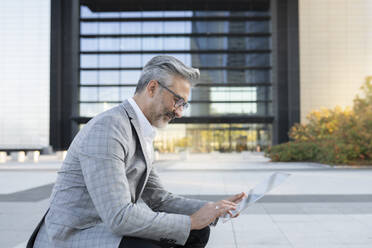 Geschäftsmann mit tragbarem Glasgerät vor einem Bürogebäude - JCCMF04414